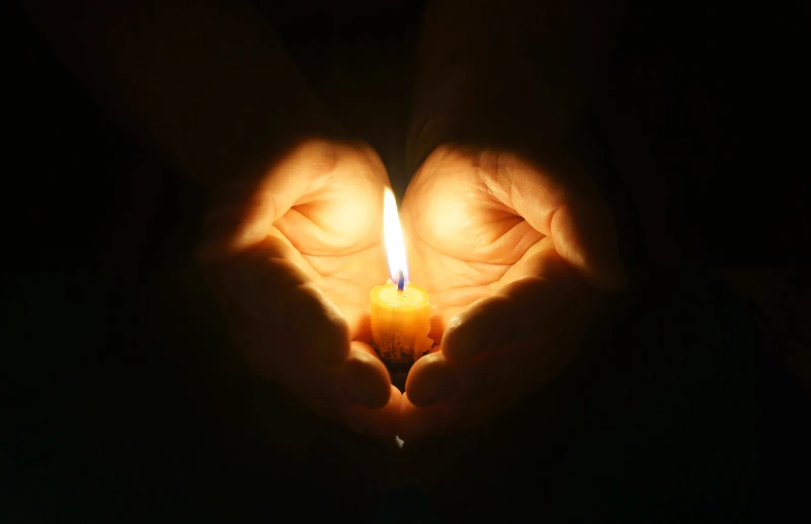 Hand holding small burning candle