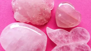 Assorted light pink rose quartz gemstones, three of which are shaped and carved